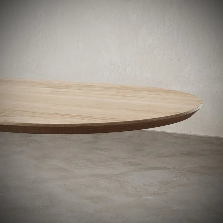 Angled view of Vangeance Oval Table highlighting its sleek oval surface edges.